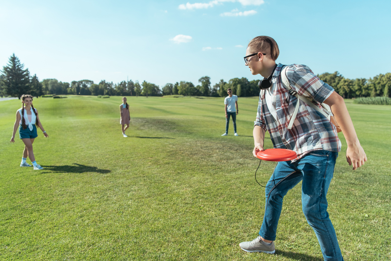 teens playing frisbee in the park