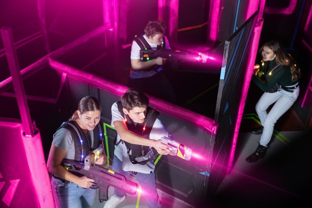 Team of young people play laser tag in a labyrinth