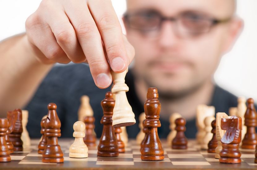 chessboard, chess pieces, man holding a chess piece