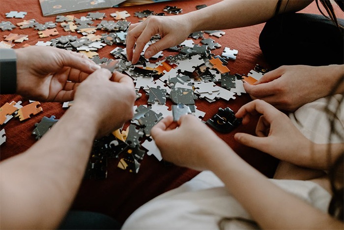 people playing puzzle, various hands working, puzzle, assembling a puzzle