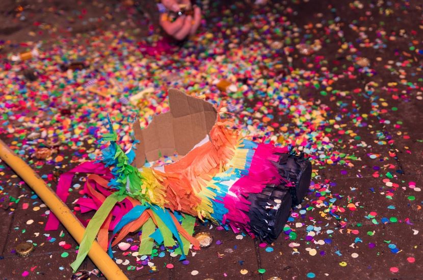 piñata on the floor, confetti, bottle caps, hand, stick