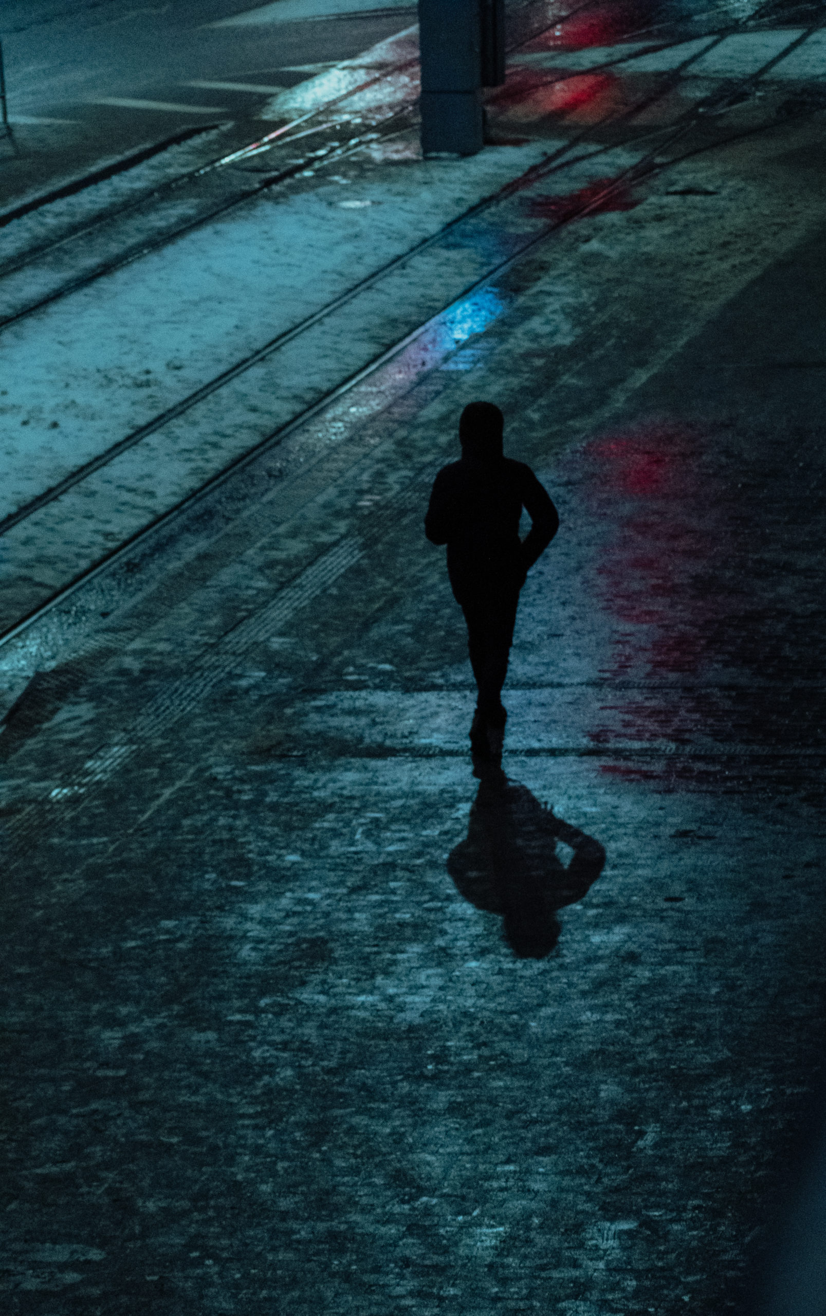 a silhouette of a person walking down the street at night